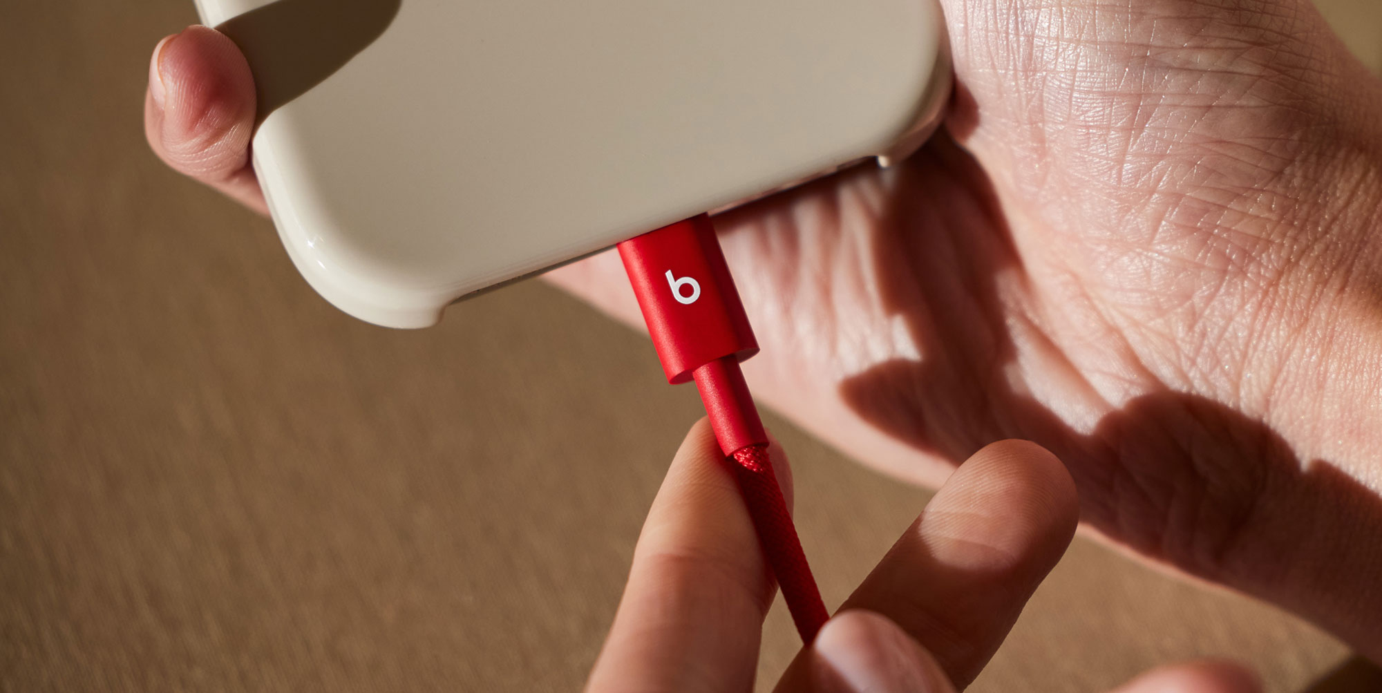 Person plugging a Beats USB-C to USB-C Woven Cable into a compatible device.