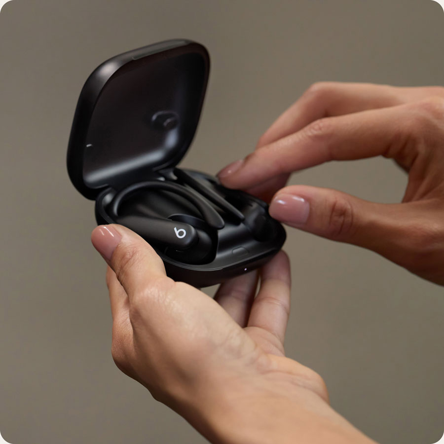 Close-up of person holding Powerbeats Pro 2 earbuds in open case